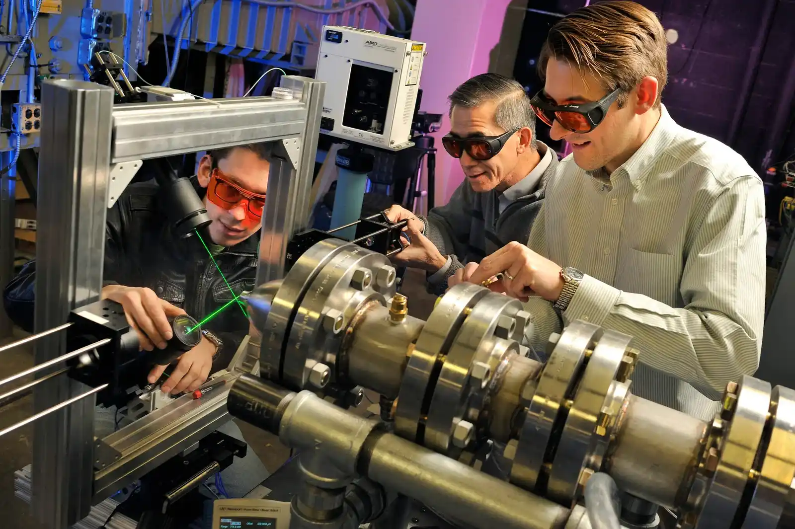 Mechanical engineers analyzing technical drawings while operating a machine in an industrial workshop